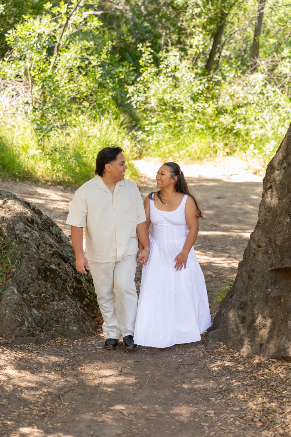 Monique and Neal walking hand in hand along a tree-lined path