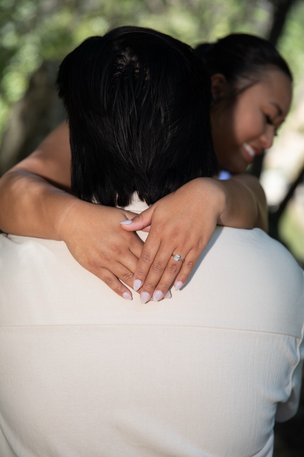 Monique and Neal embracing, engagement ring in view
